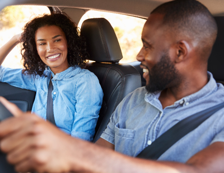 A couple smiling in their car.